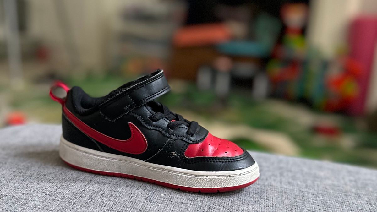 Photo of a toddler sneaker on a couch with cluttered room in background